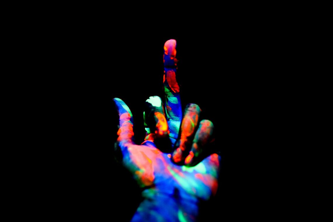crop unrecognizable person showing middle finger in darkness